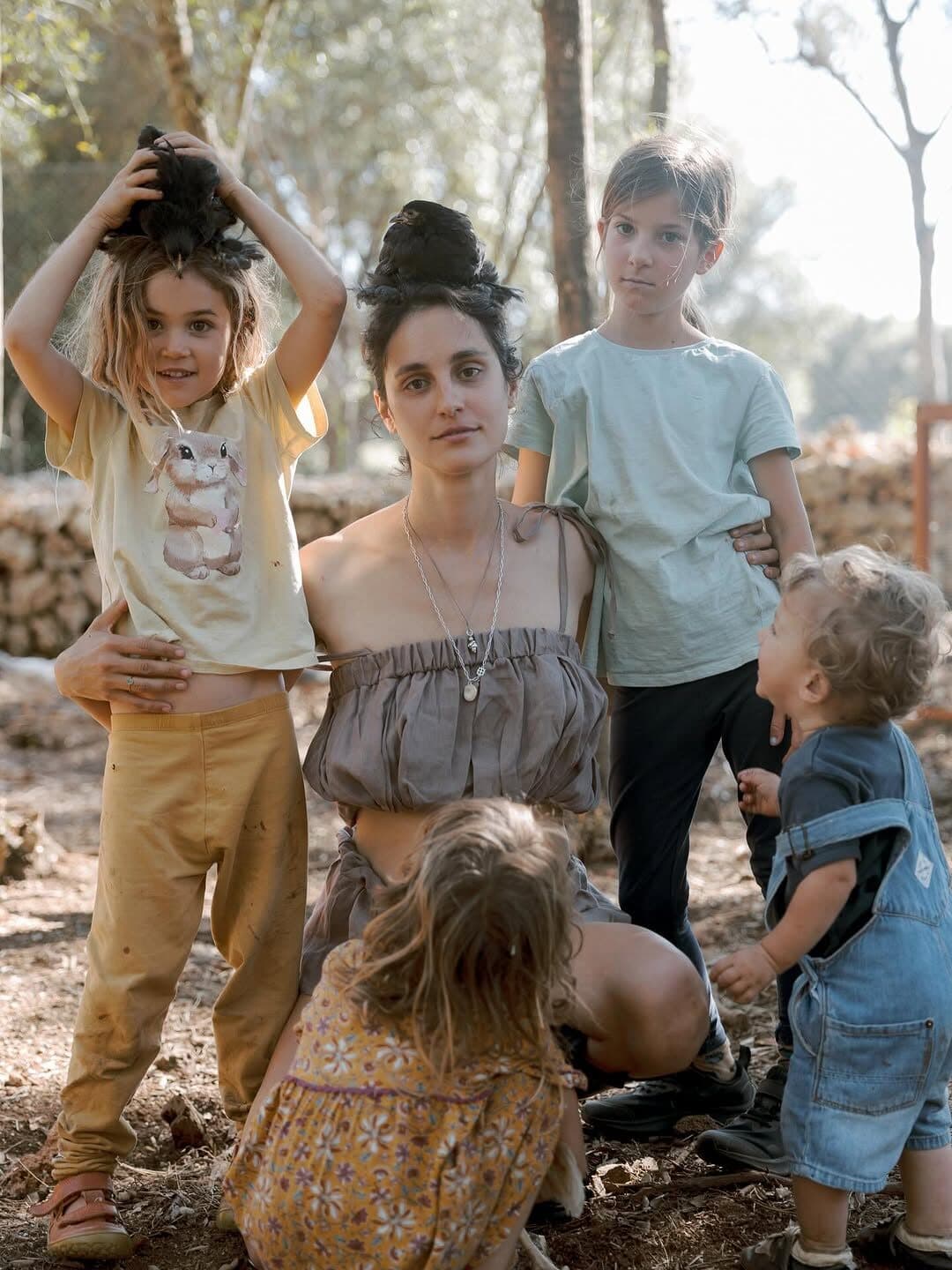 ema with her four children on the land, a chicken perched among them